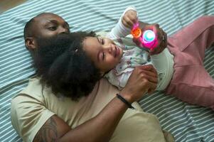 Happy African American father playing with his girl in bedroom at home photo