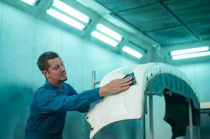 Caucasian man is cleaning car parts before spraying color in repair mechanic painting shop photo