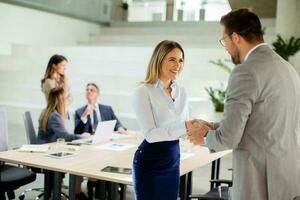 Young business woman handshaking with his colleague in the office photo