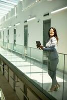 Young woman working on digital tablet in the office hallway photo