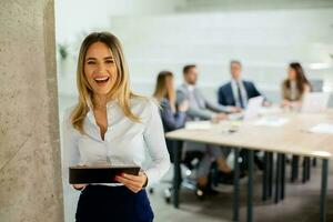 Young business woman with digital tablet in the office hallway photo