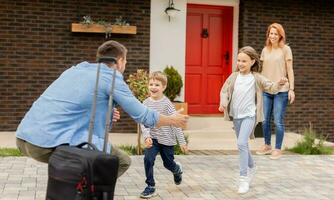 Father came home from the trip and son, daughter and wife running to meet him photo