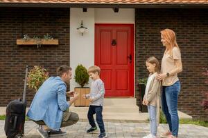 Father came home from the trip and son, daughter and wife running to meet him photo