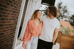 Smiling young couple in love walking  in front of house brick wall photo