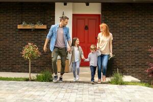 Family with a mother, father, son and daughter walking outside on the front porch of a brick house photo