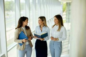 Three young business women having a discussion while walking in the office hallway photo