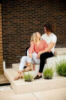 Smiling young couple in love sitting in front of house brick wall photo