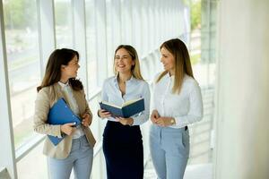 Three young business women having a discussion while walking in the office hallway photo