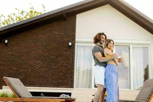 Young couple relaxing by the swimming pool in the house backyard photo