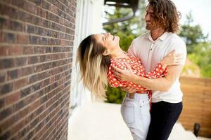 Smiling young couple in love standing in front of house brick wall photo