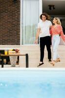 Young couple relaxing by the swimming pool in the house backyard photo