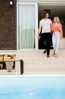 Young couple woling down on stairs by the swimming pool in the house backyard photo