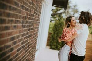 Smiling young couple in love in front of house brick wall photo