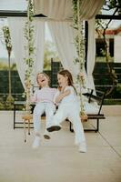 Cute little girls on the swing in the house backyard photo