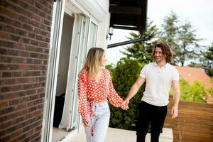 Smiling young couple in love walking in front of house brick wall photo