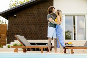 Young couple relaxing by the swimming pool in the house backyard photo