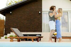 Young couple relaxing by the swimming pool in the house backyard photo