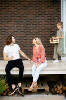 Family with a mother, father and daughter sitting outside on the steps of a front porch of a brick house photo