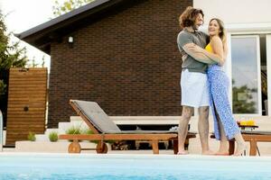 Young couple relaxing by the swimming pool in the house backyard photo