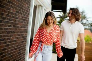 Smiling young couple in love walking in front of house brick wall photo