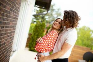 Smiling young couple in love standing in front of house brick wall photo