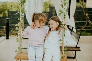 Cute little girls on the swing in the house backyard photo