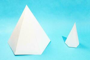 pair of different paper pyramids on turquoise blue photo