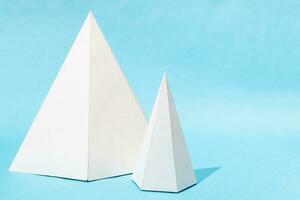 paper big and small lying pyramids on turquoise photo