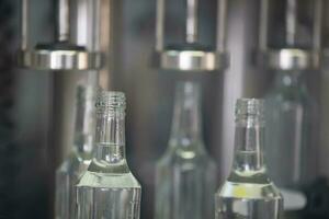 A row of glass bottles on a conveyor belt for the production of alcoholic beverages. photo