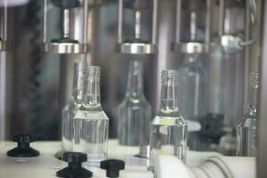 A row of glass bottles on a conveyor belt for the production of alcoholic beverages. photo