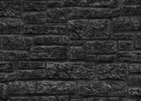 Black brick wall with gray spots. Texture of a rough dark wall. photo