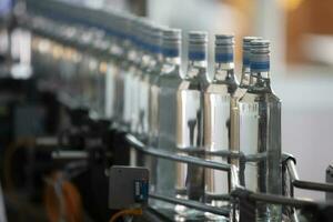 A long row of glass bottles on a conveyor belt. Production of alcoholic beverages. photo