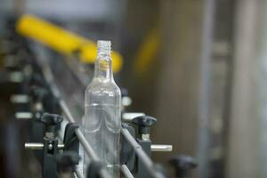 A long row of glass bottles on a conveyor belt. Production of alcoholic beverages. photo