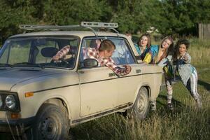 joven alegre muchachas son emprendedor un antiguo coche. mujer en el estilo de el años 90 foto