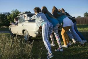 joven alegre muchachas son emprendedor un antiguo coche. mujer en el estilo de el años 90 foto