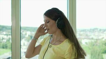 Young happy woman dancing cheerful listening to music wearing headphones inside apartment video