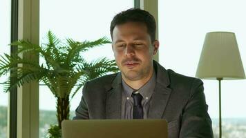 a man in a suit and tie sitting at a desk with a lap working in finance business jobtop video