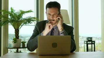 a man in a suit and tie sitting at a desk with a lap working in finance business jobtop video