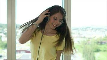 Jeune content femme dansant de bonne humeur écoute à la musique portant écouteurs à l'intérieur appartement video