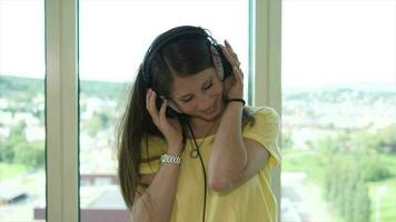 Young happy woman dancing cheerful listening to music wearing headphones inside apartment video