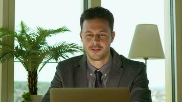 a man in a suit and tie sitting at a desk with a lap working in finance business jobtop video