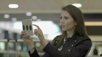 Young confident woman using mobile tablet device on business trip video