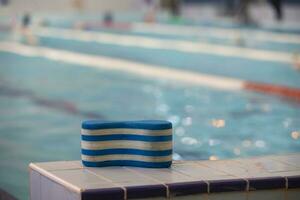 The striped swim training tool rests on the side of the pool. photo