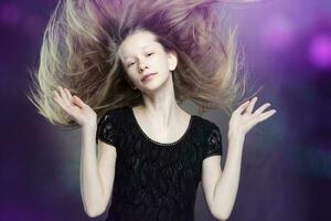 en contra un púrpura fondo, un hermosa Adolescente niña aleteado su cabello. foto