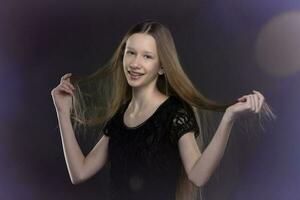 Teenage girl with long hair in a black dress on a background of colored bokeh. photo