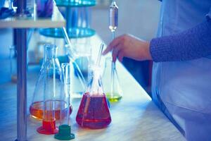 Vaccine production laboratory. Glass flasks with a chemical liquid in infrared radiation. photo