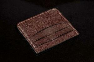 Leather brown business card holder on a black background. photo