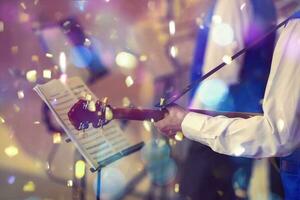 musical evento. manos de un músico con un guitarra en frente de un nom en brillante papel picado. foto