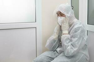 Exhausted doctor in protective medical clothing during the coronavirus epidemic. photo