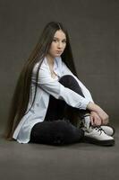 Beautiful brunette girl with very long hair on a gray background. photo